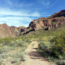 The trail as it heads into the canyon with the arch on top of high rocky cliffs