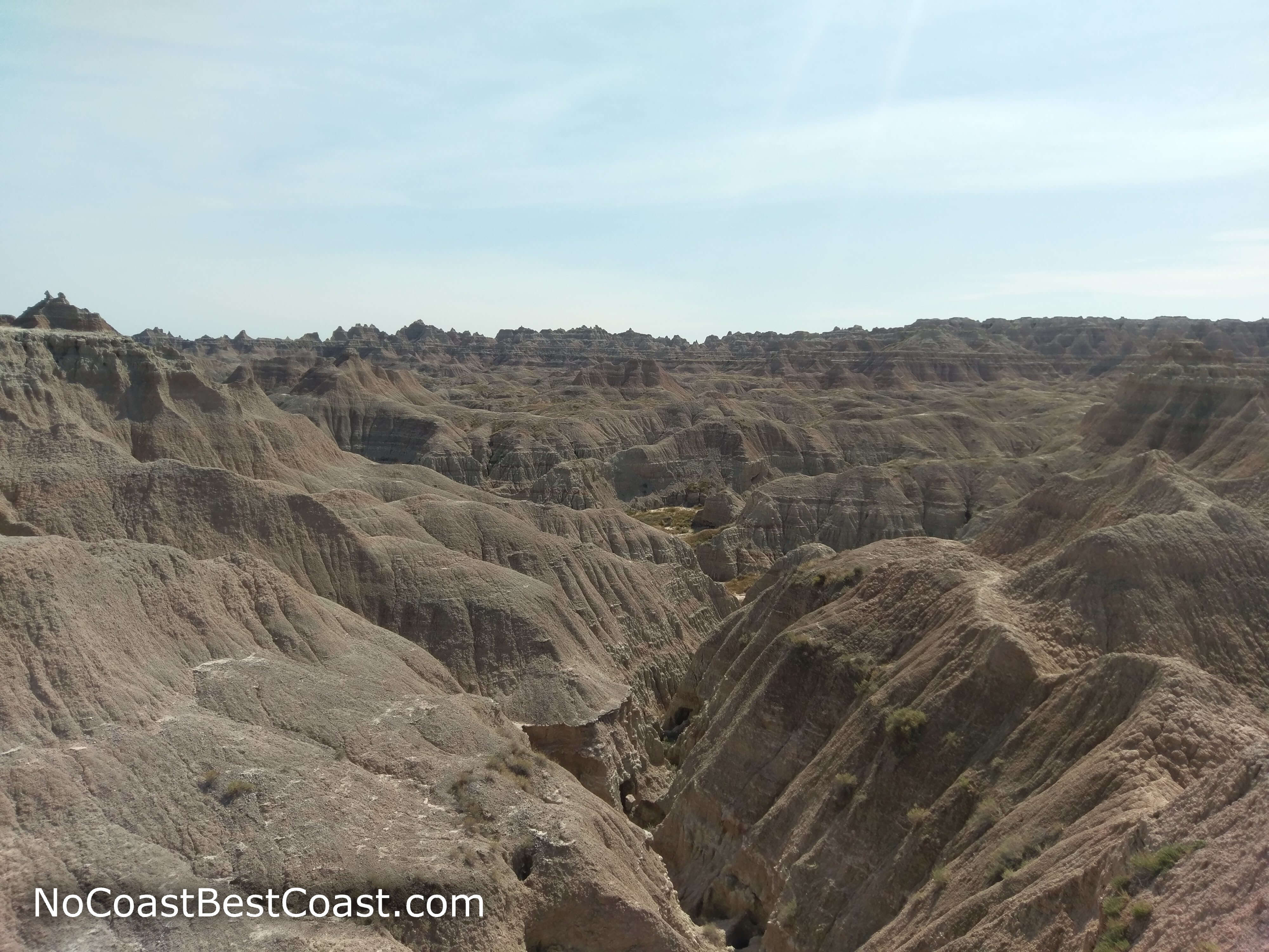 As you stand on top of a badlands formation, you can see down into the water-carved canyons below