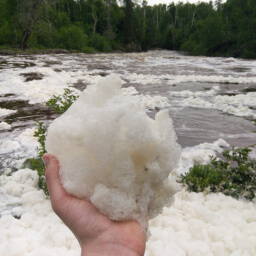 Snowy globs of foam cover the surface of the river